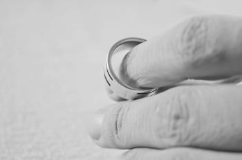 Hand Holding Wedding Ring after being Served Divorce Papers